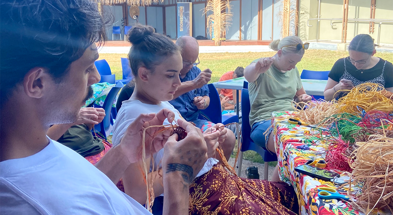 A group sits around a table weaving small, colourful items at the Gag Titui Cultural Centre on Thursday Island. 